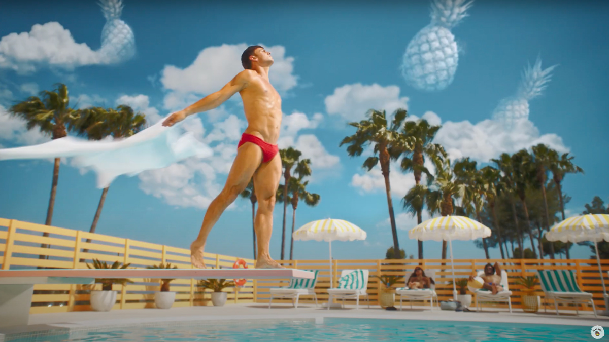 Tom Daley wearing red swimming briefs standing on a diving board.