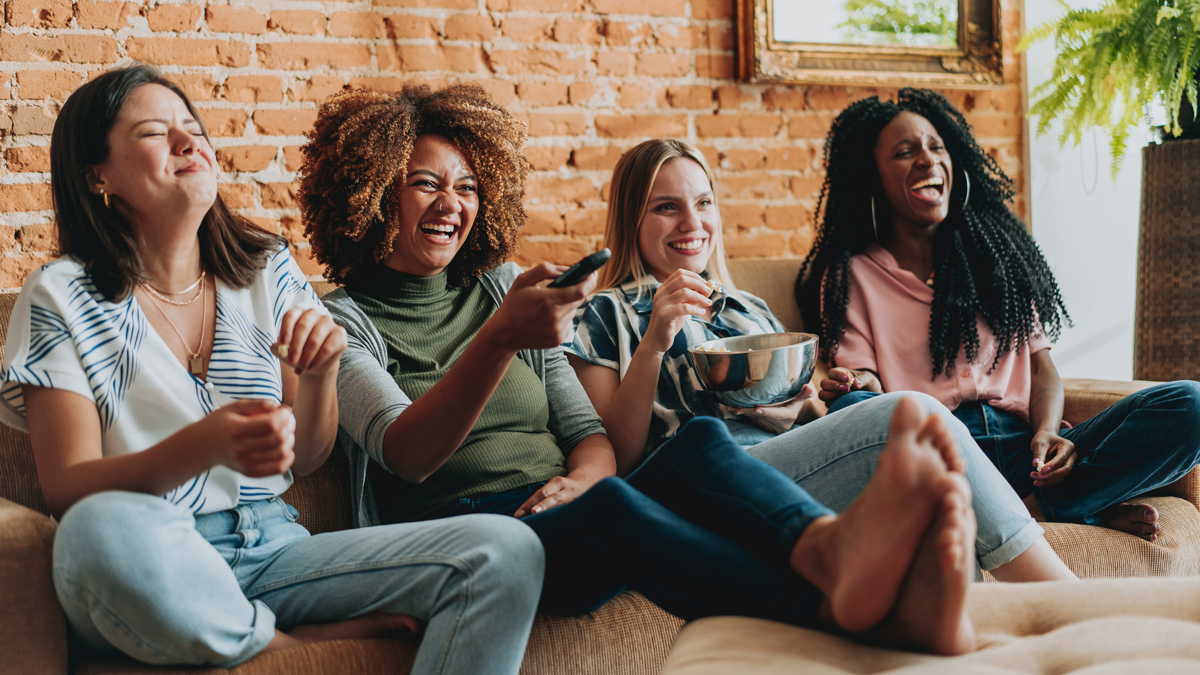 four women laughing together on a sofa