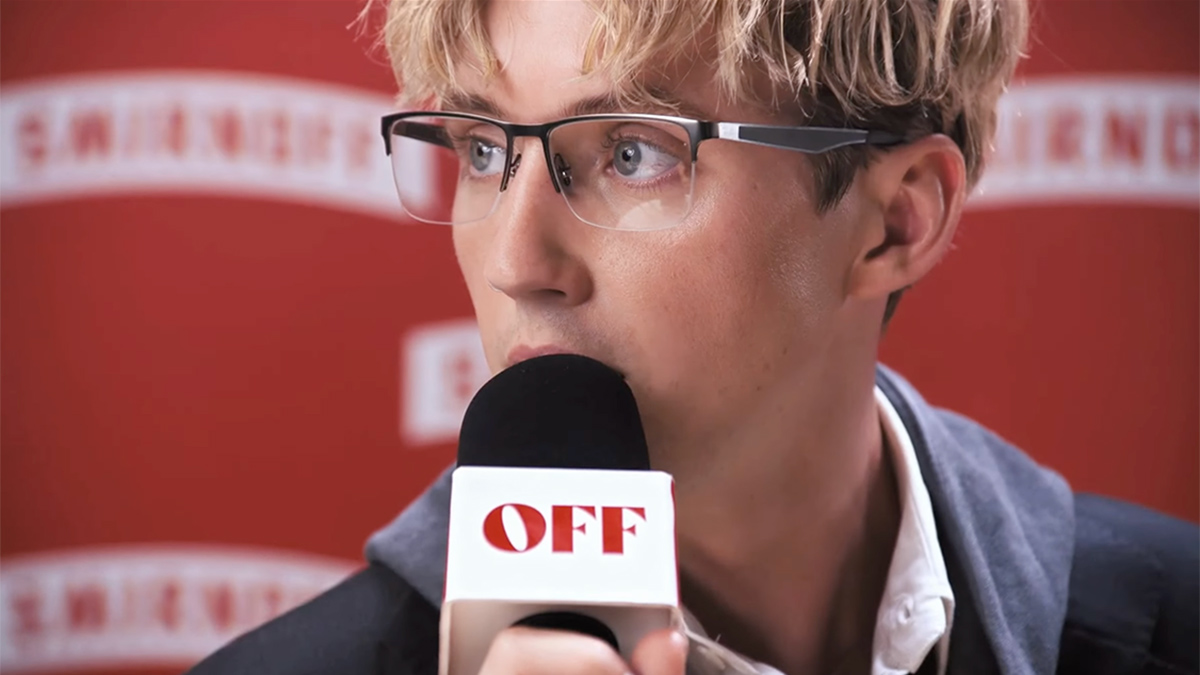 Troye Sivan holds a microphone that says off.