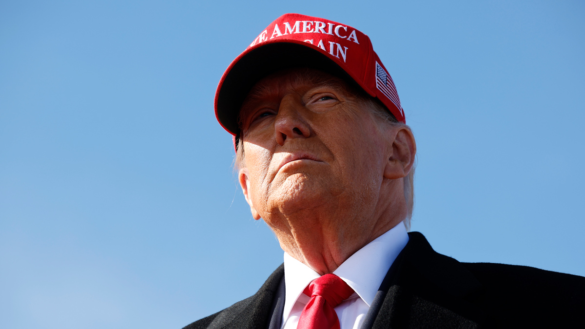 Close-up of Donald Trump wearing a suit, red tie and red hat that reads Make America Great Again.